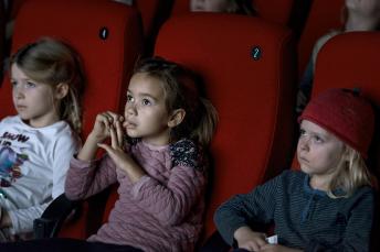 Tre børn i biograf kigger op mod lærredet